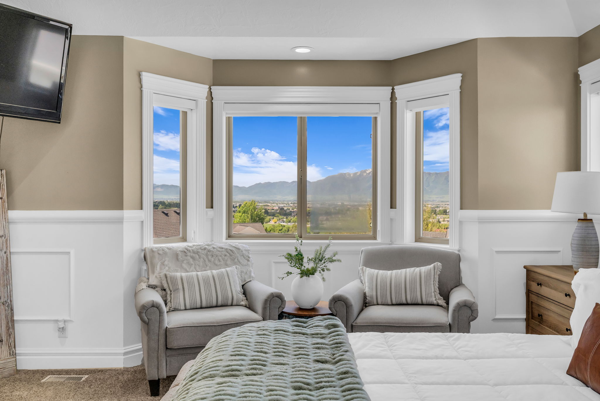 Bay window with mountain scenery, framed by extensive white trim and wainscoting