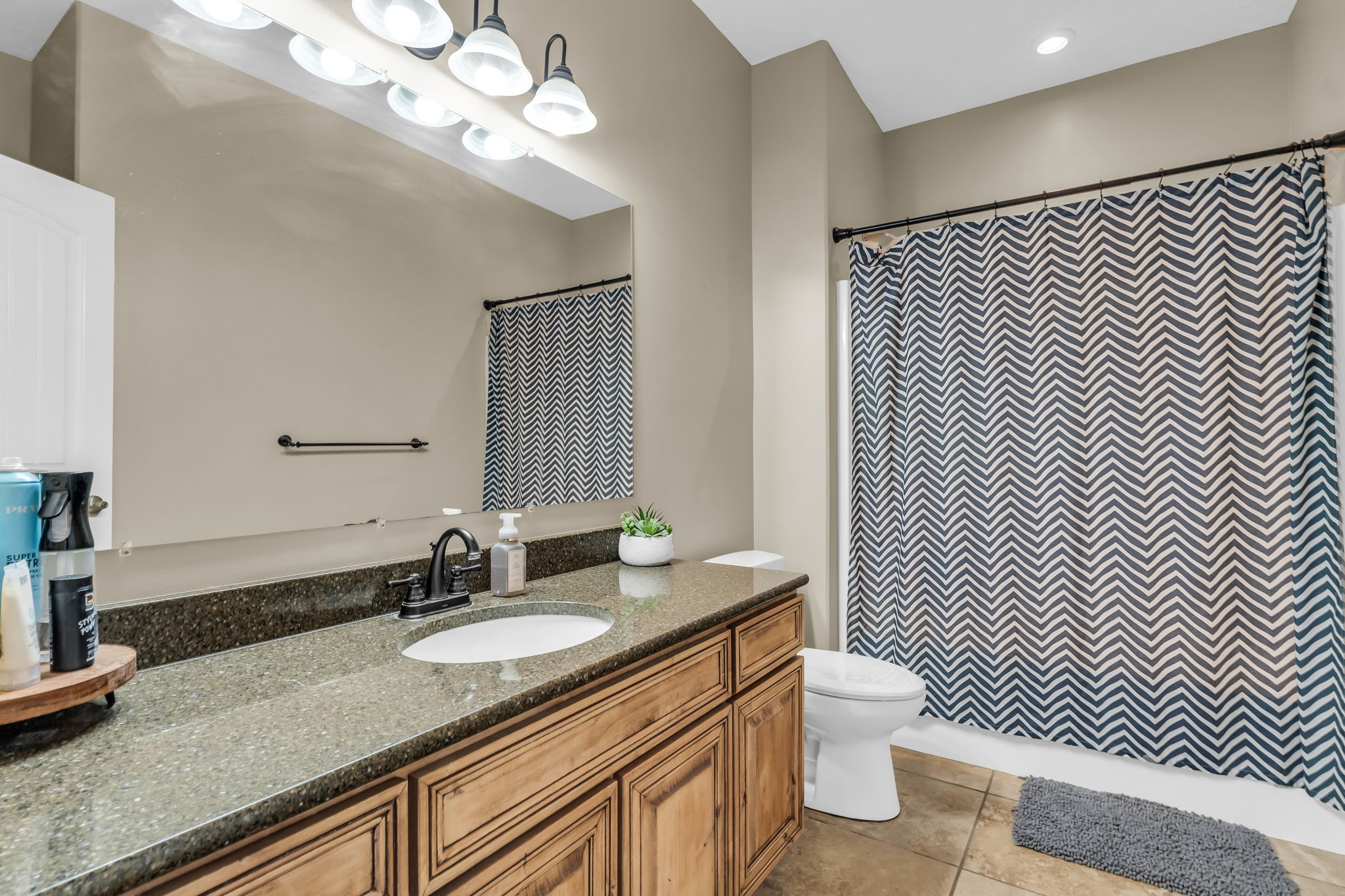 Bathroom vanity with a dark speckled countertop, undermount sink, and matte black faucet