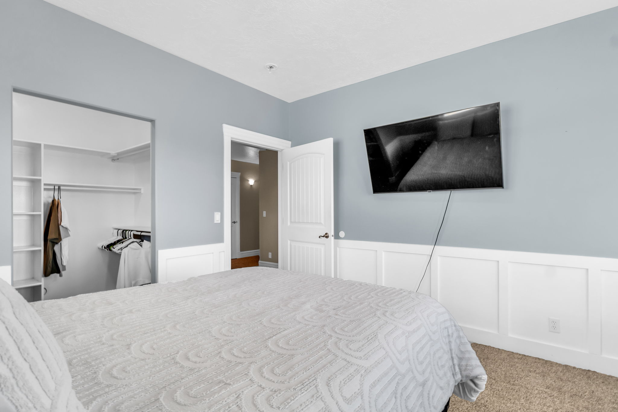 Bedroom featuring board and batten wall detailing, light blue painted walls, and carpet flooring