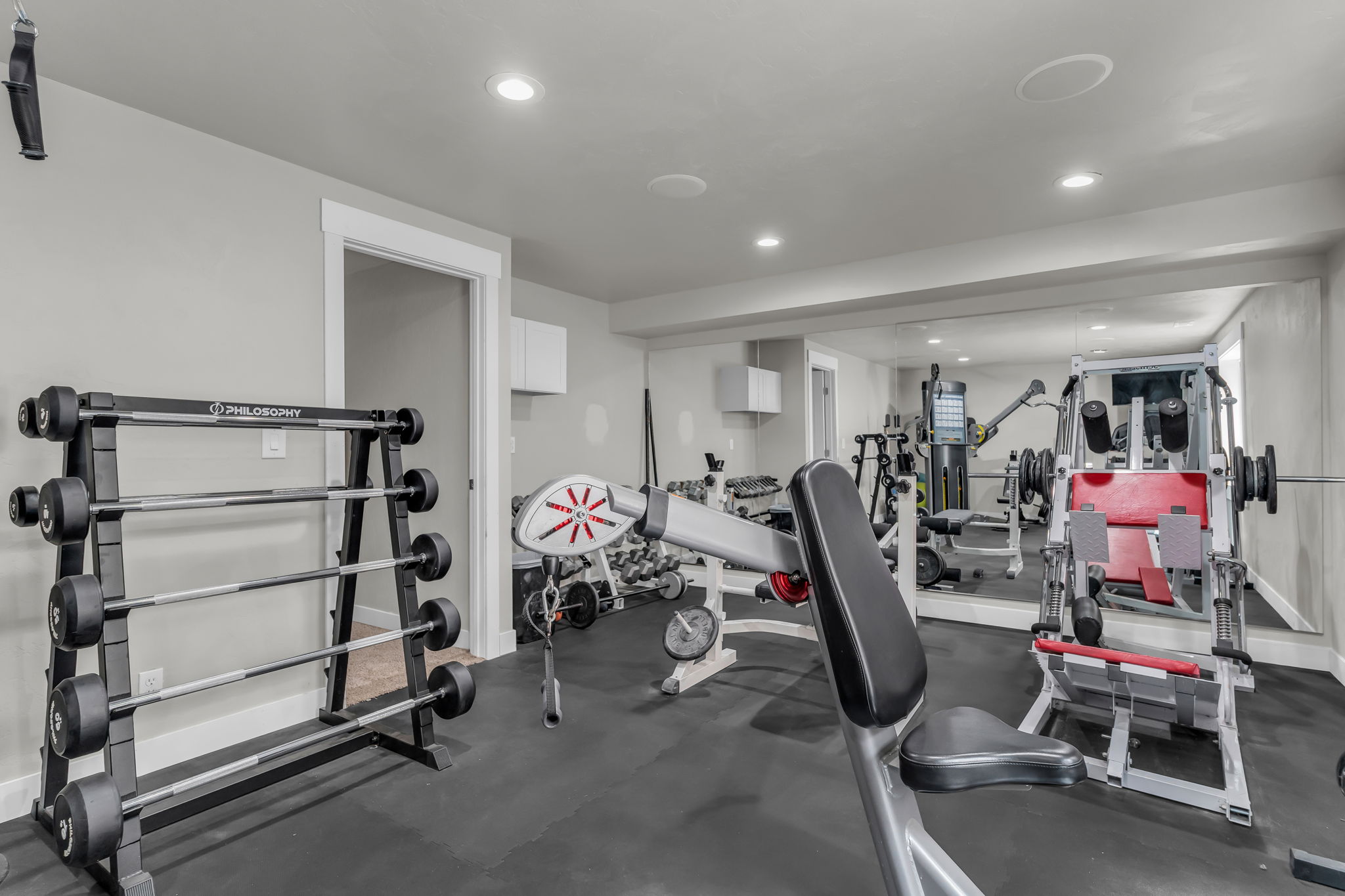 Dedicated fitness area featuring rubber flooring, recessed lighting, and a full-wall mirror
