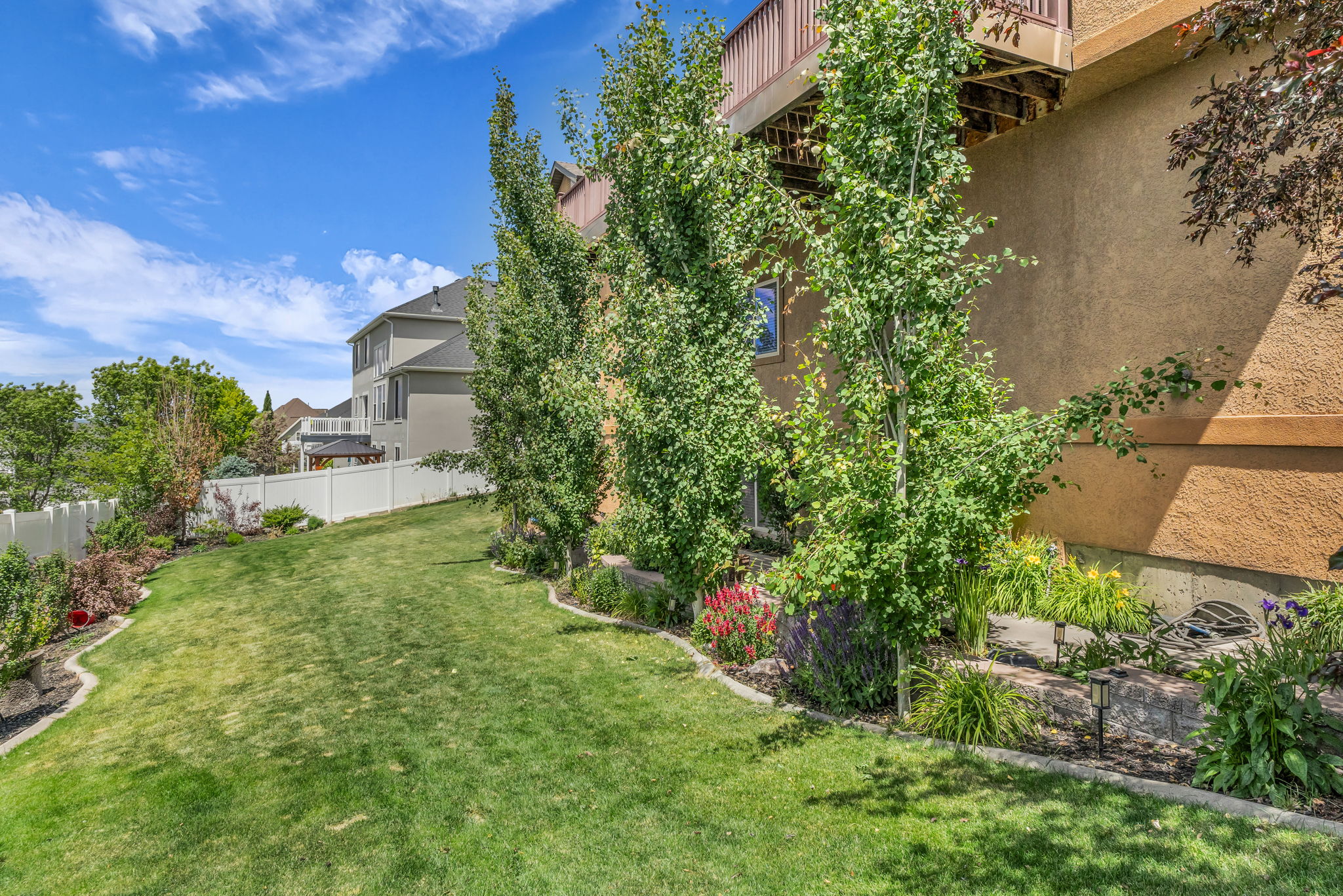 Terraced backyard featuring a sloped lawn and mature trees