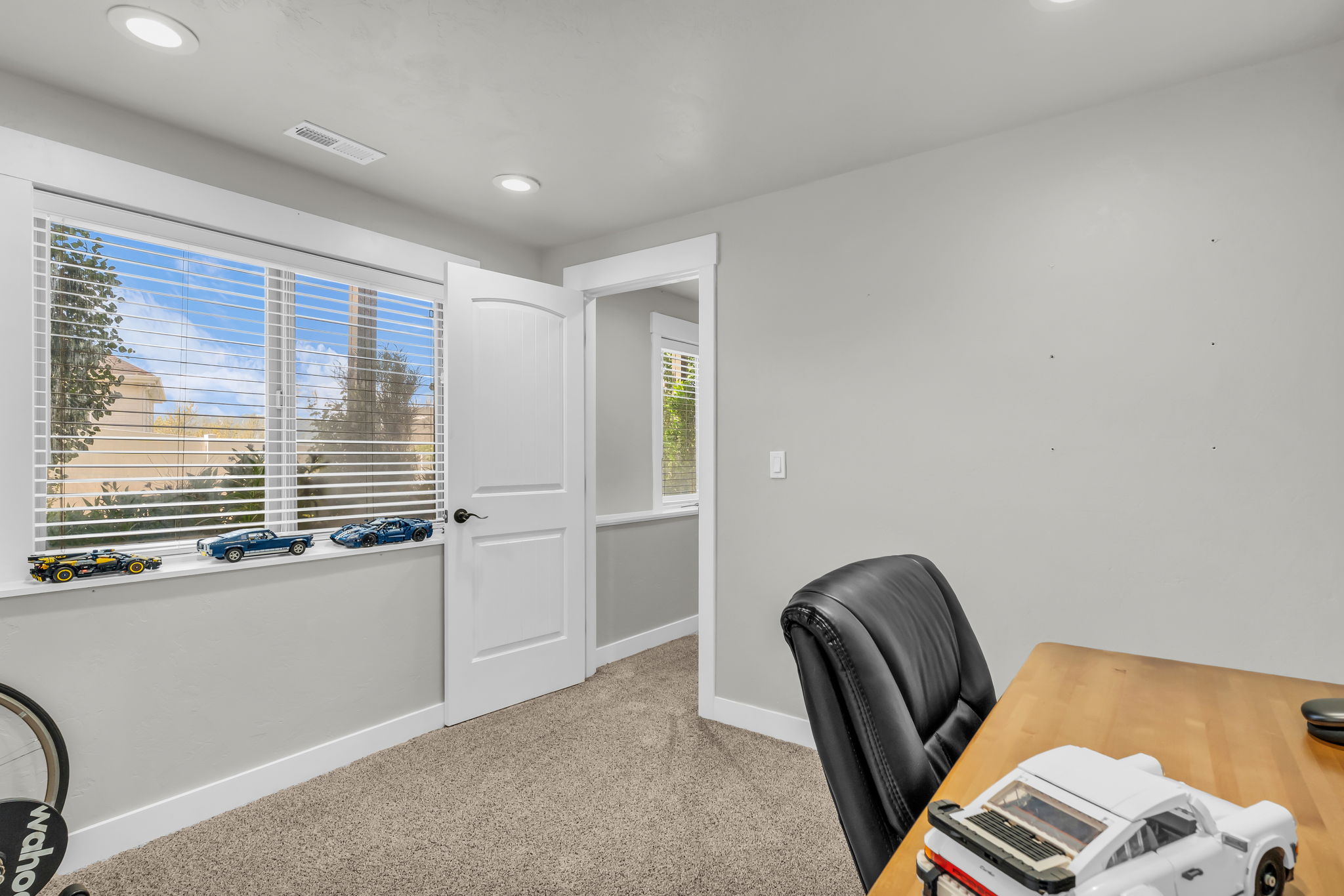 Room featuring a large window with white blinds, neutral carpeting, recessed lighting, and crisp white trim