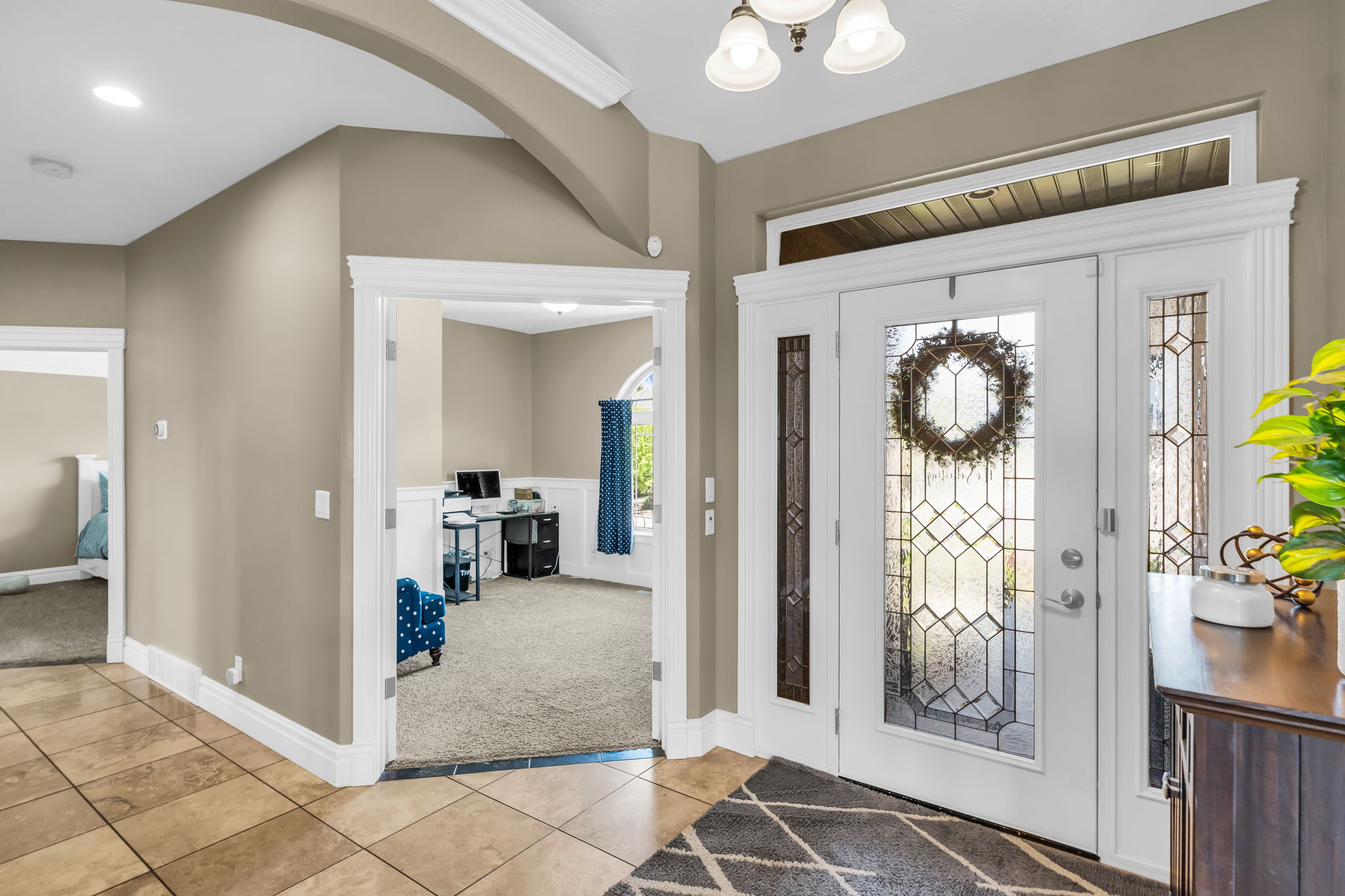 Entryway featuring a decorative transom and sidelight windows, overhead lighting, arched wall detailing, and tile flooring