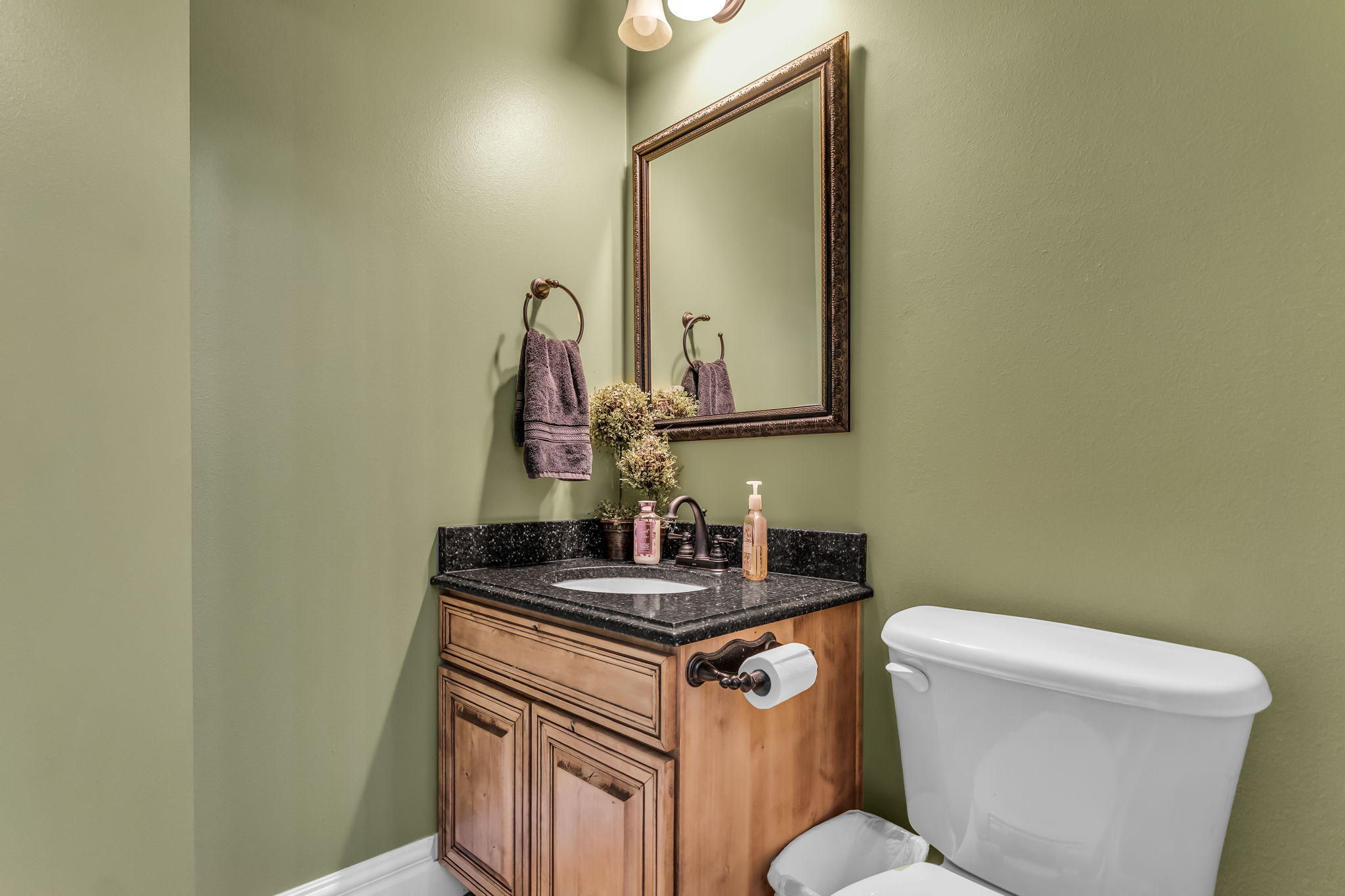 Bathroom vanity with a dark speckled countertop, an undermount sink, and a bronze-finish faucet