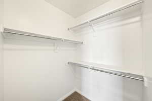 Walk-in closet featuring white shelving with chrome hanging rods, white walls, and a carpeted floor