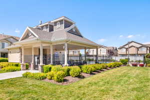 Community amenity building featuring a covered patio with stone-wrapped columns, a shingle roof, and gabled dormers