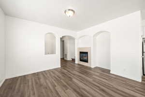 Spacious interior featuring wood-finish flooring, a contemporary fireplace with a stone surround, and arched wall niches