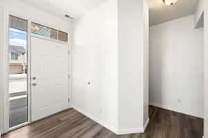 Entryway featuring a paneled door with sidelight and transom windows, wood-finish flooring, and white baseboards