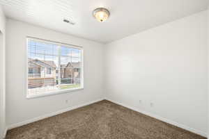 Carpeted room with a large window featuring horizontal blinds
