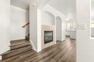 Open-concept main level featuring wood-finish flooring, a gas fireplace with tile surround, and arched architectural details