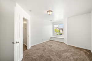Carpeted room featuring a window with a built-in sill, white trim, and a semi-flush mount ceiling light