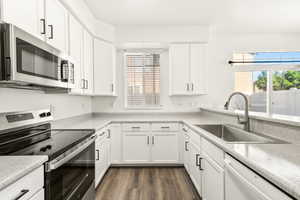 Updated kitchen featuring white shaker cabinetry, light-toned countertops, and wood-finish flooring