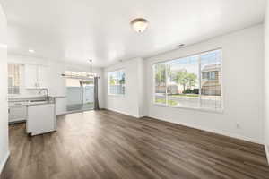 Open-concept living area with wood-finish flooring, white walls, and abundant natural light from multiple windows