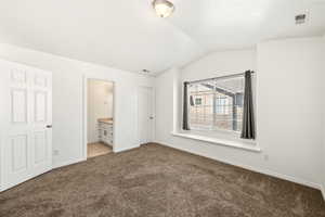 Carpeted room featuring a window with integrated seating, white trim, and a vaulted ceiling