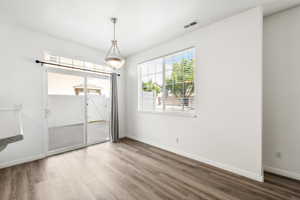 Dining area featuring wood-finish flooring, white walls, and a contemporary pendant light fixture