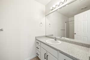 Vanity featuring a white undermount sink, chrome faucet, and speckled countertop