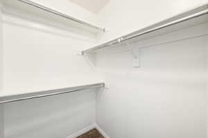 Built-in closet system featuring multiple chrome hanging rods, white shelving, and neutral carpeting
