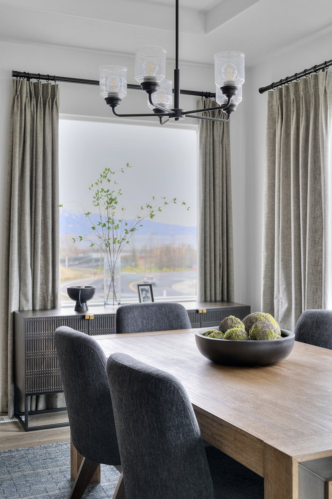 Dining area featuring a wood-finish table, upholstered chairs, and a black chandelier with clear glass shades
