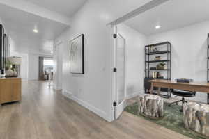 Dedicated office space with a glass-paneled door, recessed lighting, wood-finish flooring, and crisp white walls