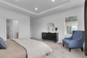 Spacious bedroom featuring a tray ceiling with recessed lighting, carpet flooring, and a large window
