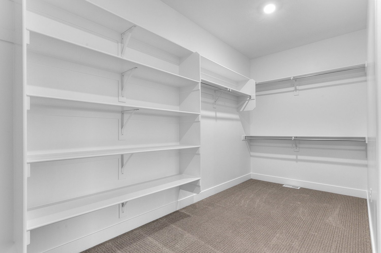 Spacious walk-in closet featuring extensive built-in shelving, multiple hanging rods, recessed ceiling lighting, and carpet flooring