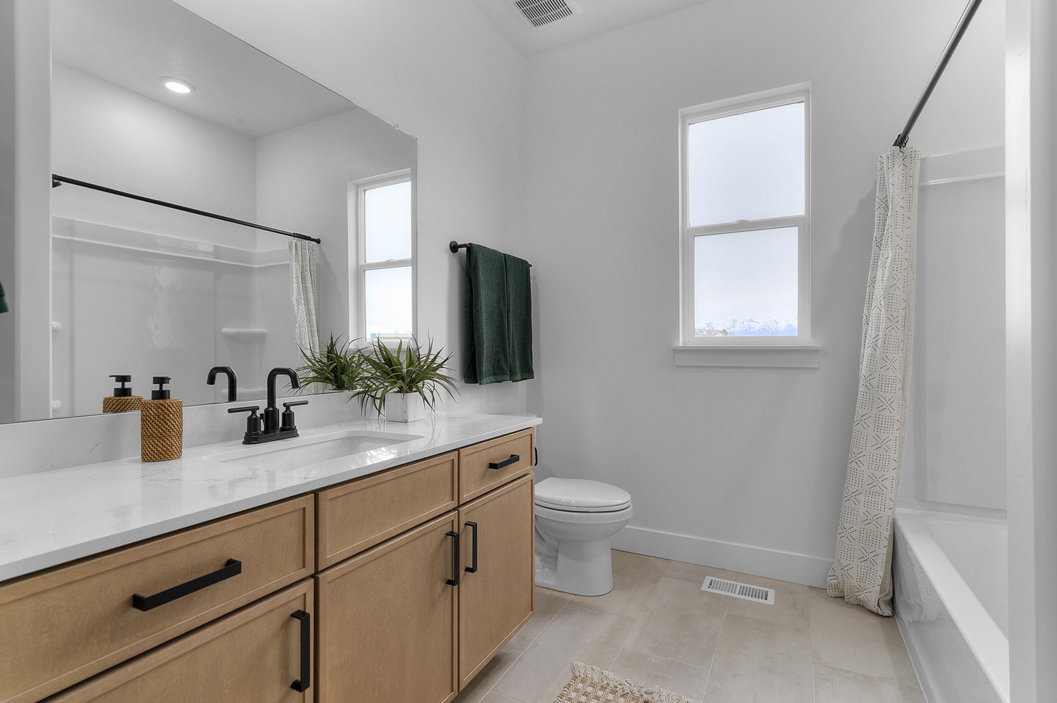 Bathroom featuring a light wood-finish vanity with black hardware, white countertop, and integrated sink