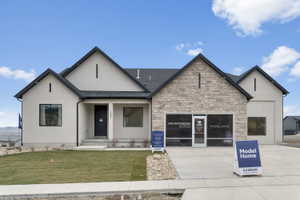Modern stucco and stone-veneer exterior with a black asphalt shingle roof