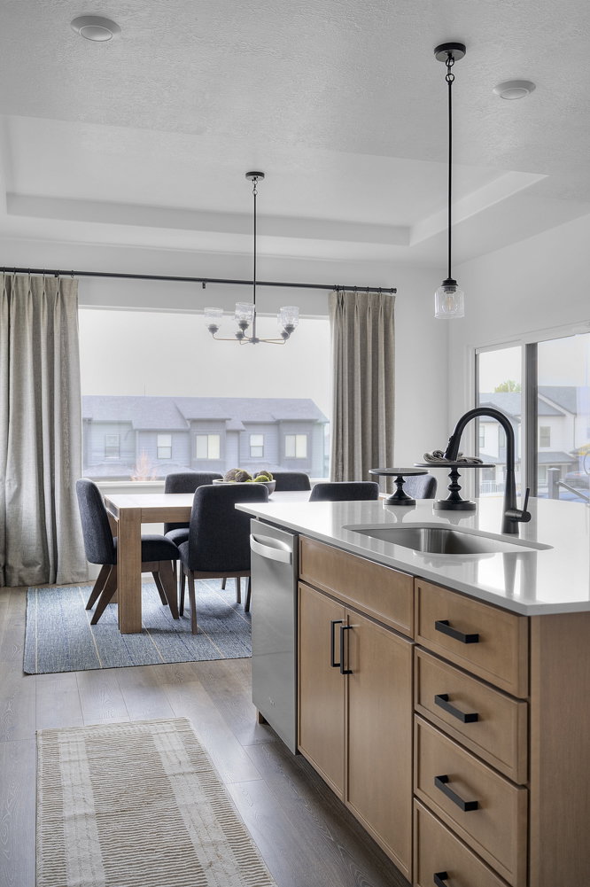 Kitchen island with wood-finish cabinetry, black hardware, and a white countertop with an undermount sink