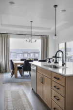 Kitchen island with wood-finish cabinetry, black hardware, and a white countertop with an undermount sink