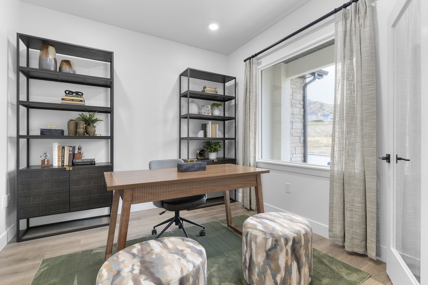 Dedicated office space featuring wood-finish flooring and a large window with exterior stone accents