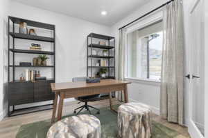 Dedicated office space featuring wood-finish flooring and a large window with exterior stone accents