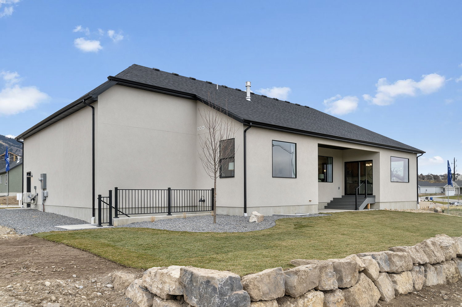 Modern stucco exterior with black-framed windows and a dark shingle roof