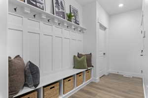 Entryway featuring a built-in bench with cubby storage, panel accent wall, and wood-finish flooring