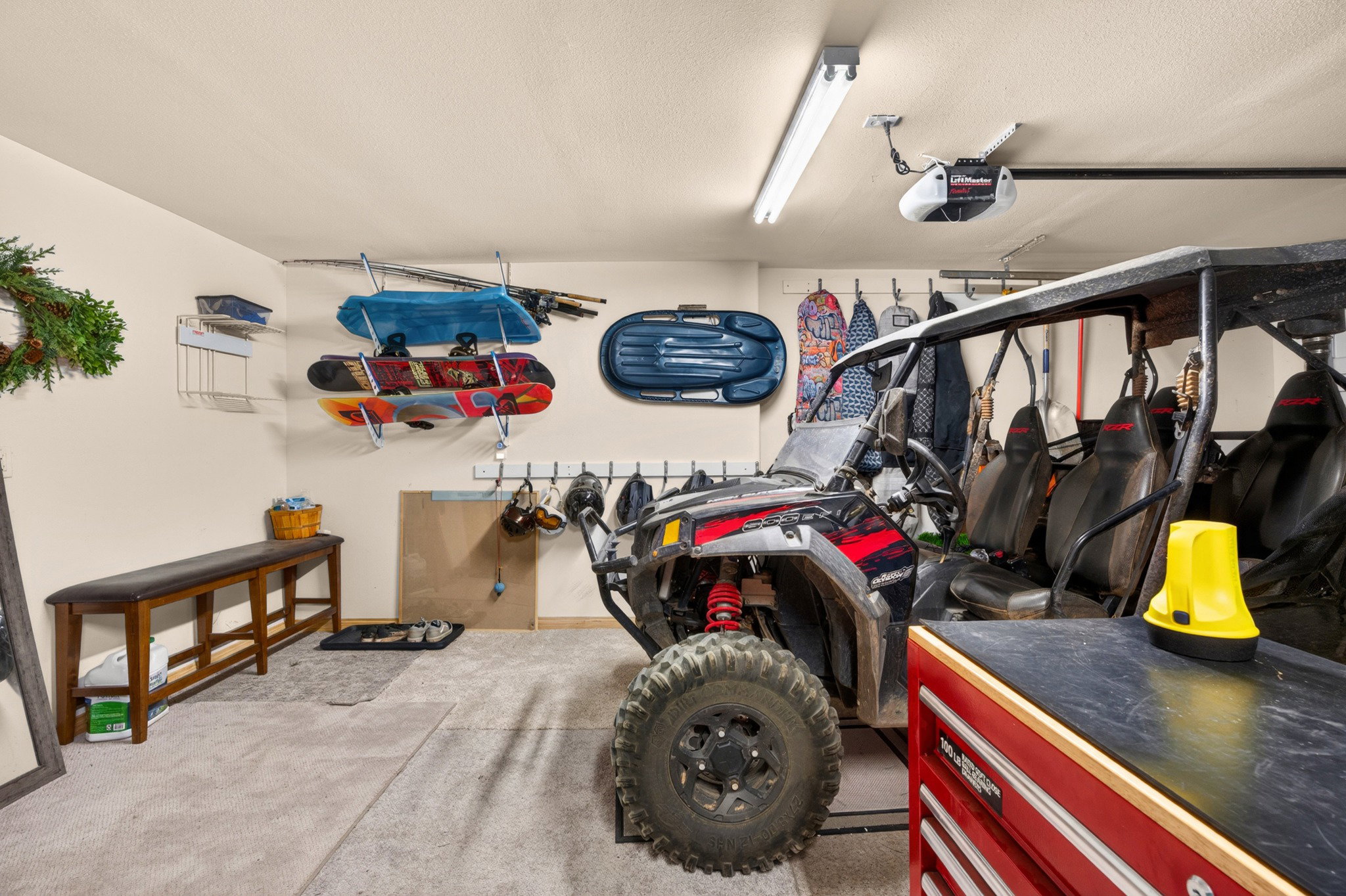 Spacious garage featuring light-toned walls, overhead fluorescent lighting, and a garage door opener system