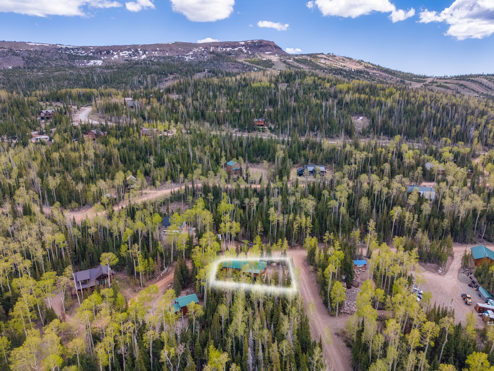 Expansive mountain property with a dense tree canopy, surrounded by additional wooded areas and distant mountain ranges