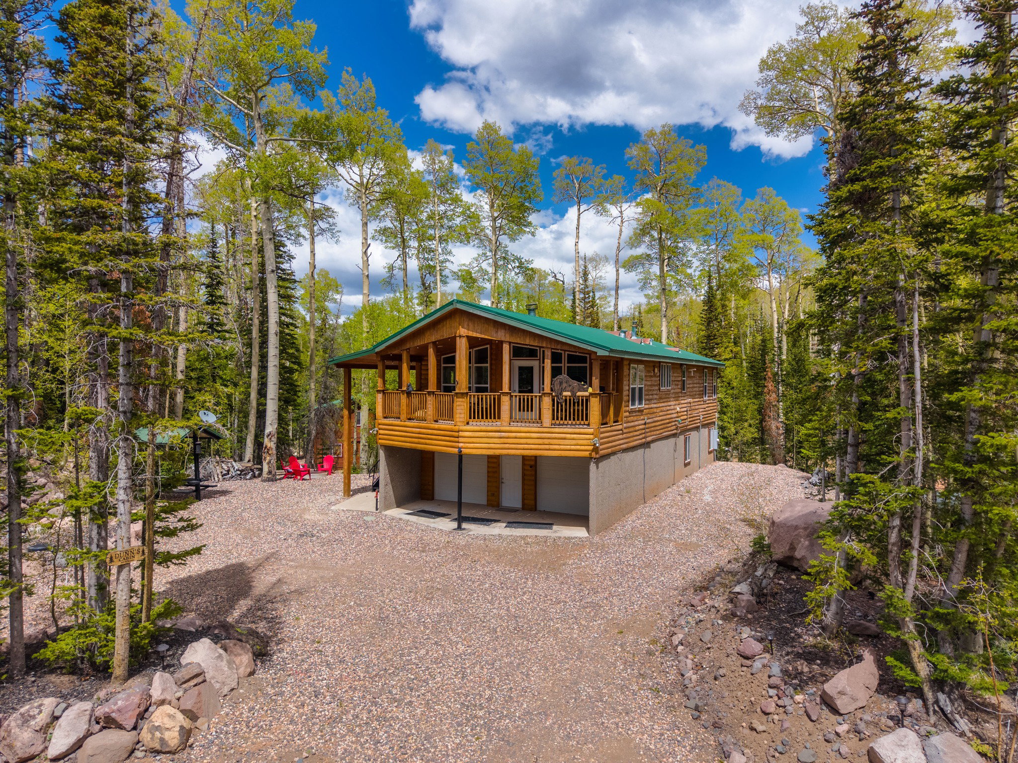 Wood-sided cabin featuring a green metal roof and an elevated porch with wood railings