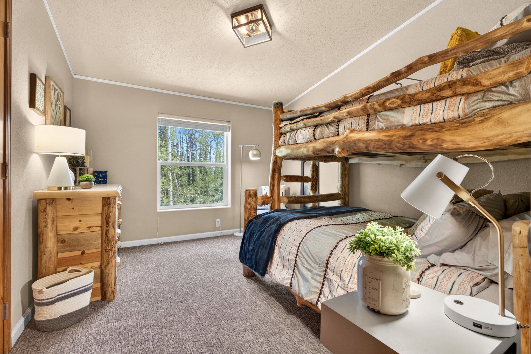 Spacious room featuring a large window, light-colored walls, and textured carpet flooring
