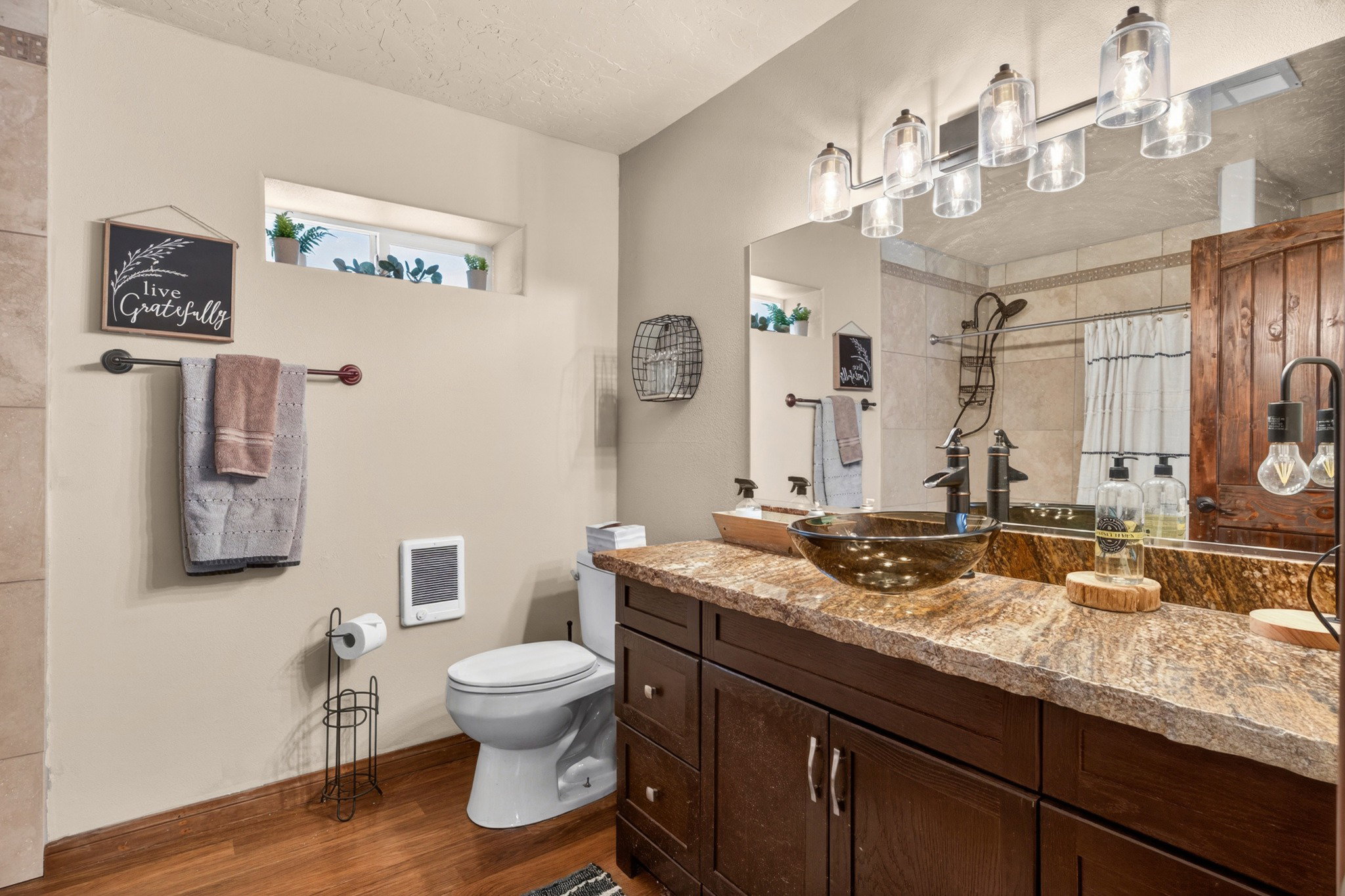 Bathroom featuring a dark wood-finish vanity with a vessel sink, a stone-finish countertop, and a large mirror
