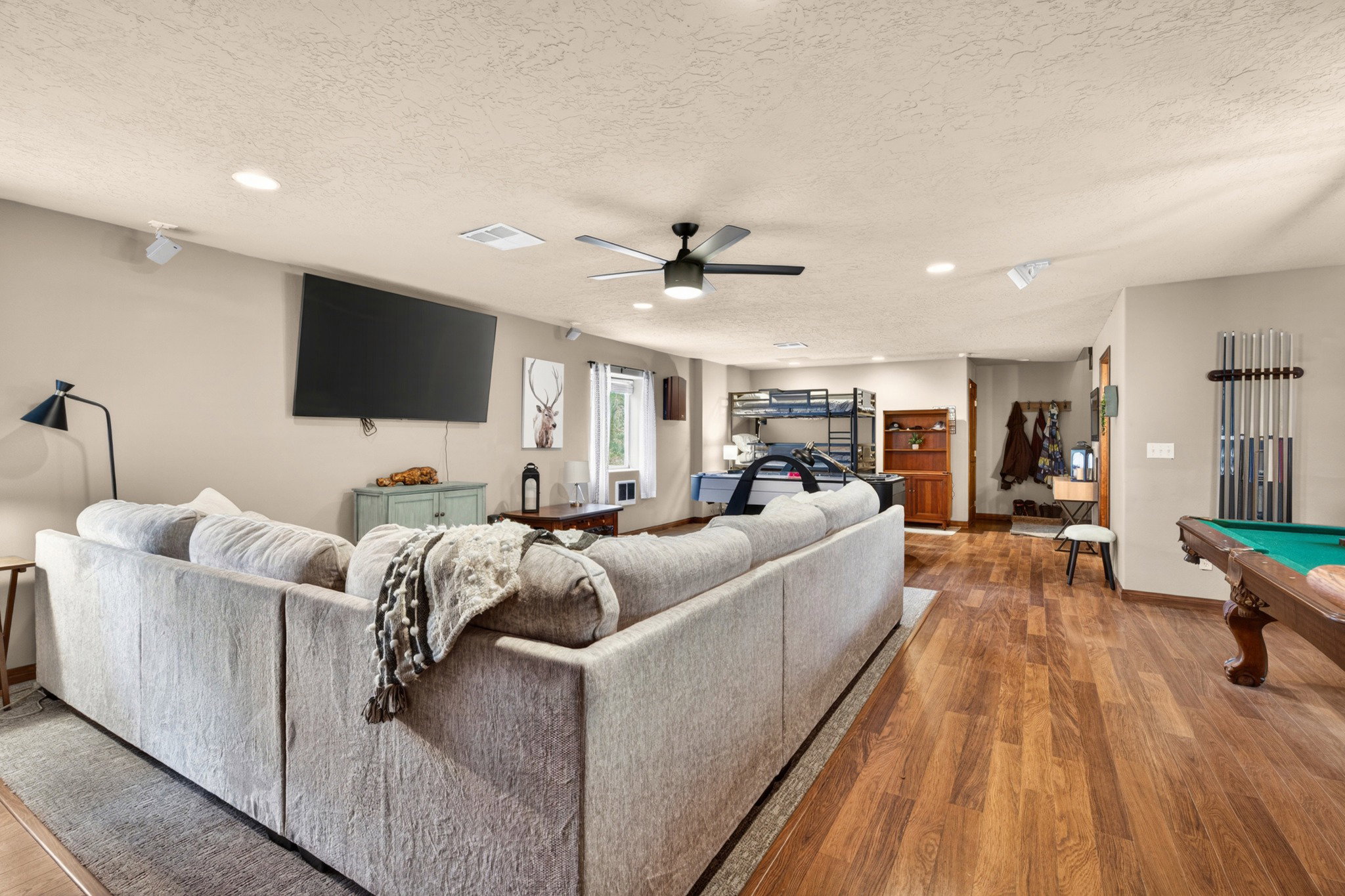 Spacious entertainment area featuring wood-finish flooring, recessed lighting, and a ceiling fan