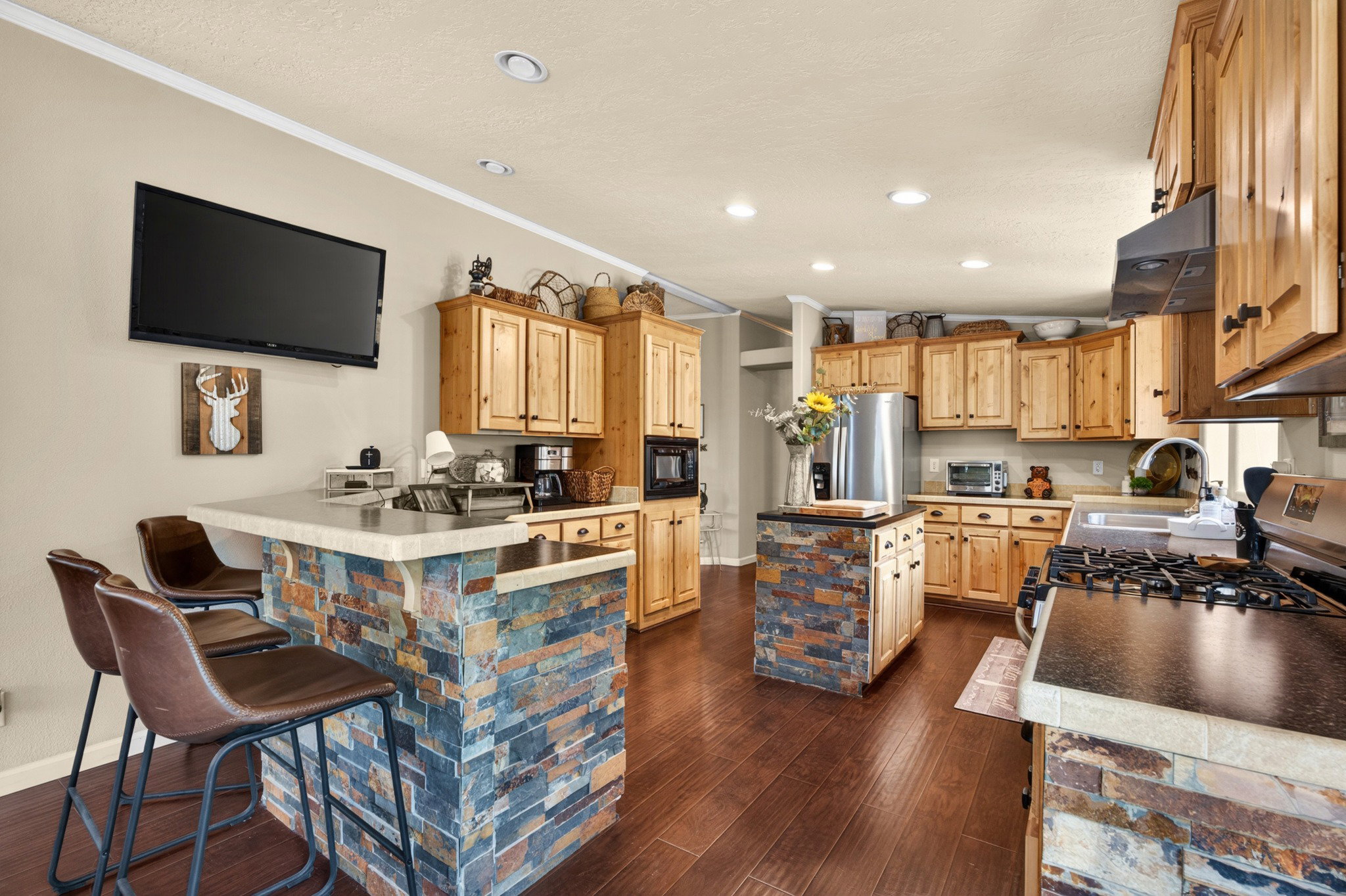 Spacious kitchen featuring wood-finish flooring, extensive wood cabinetry, and recessed lighting