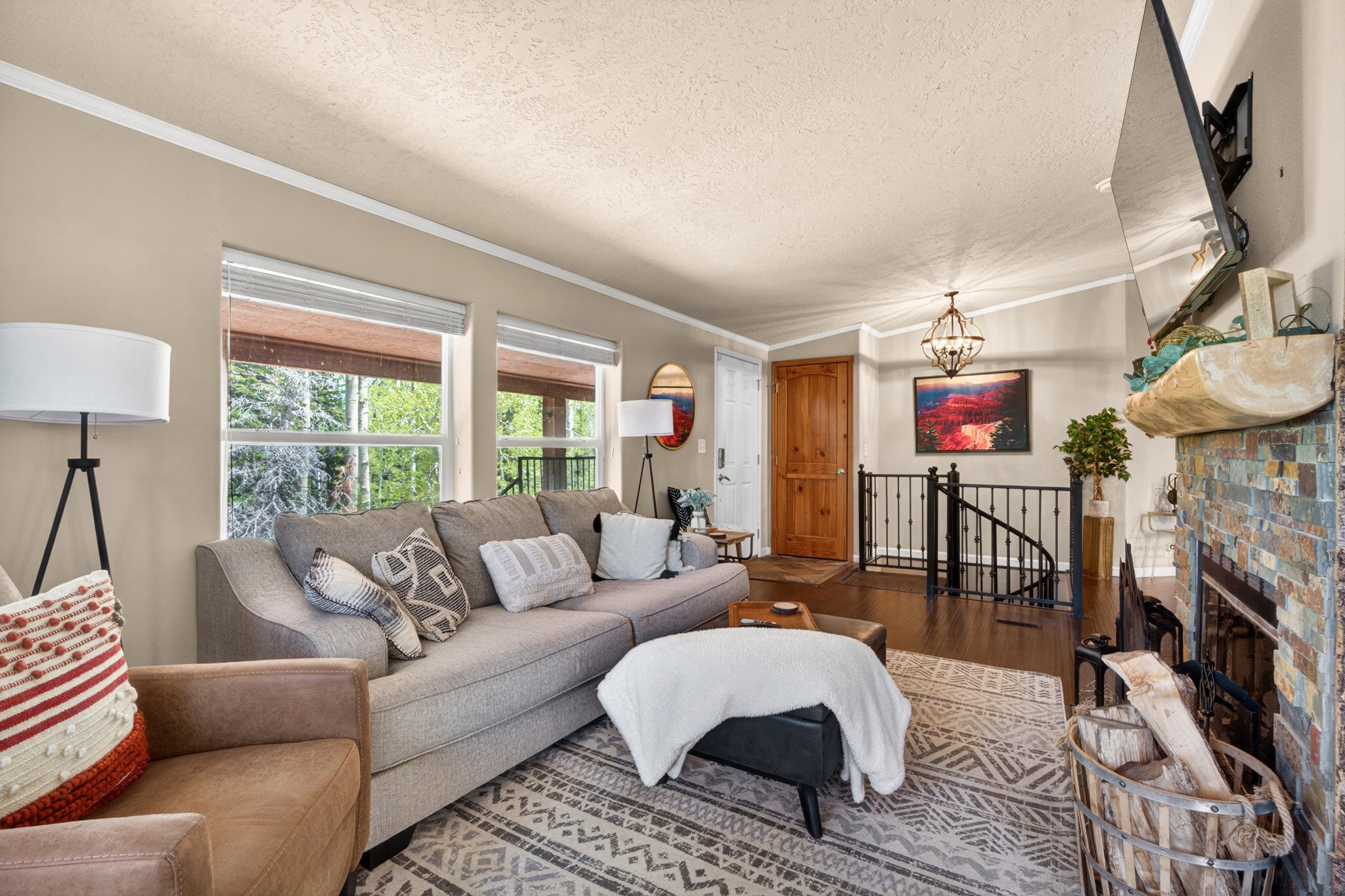 Living area featuring a stone-clad fireplace, dark wood-finish flooring, and a wrought iron spiral staircase