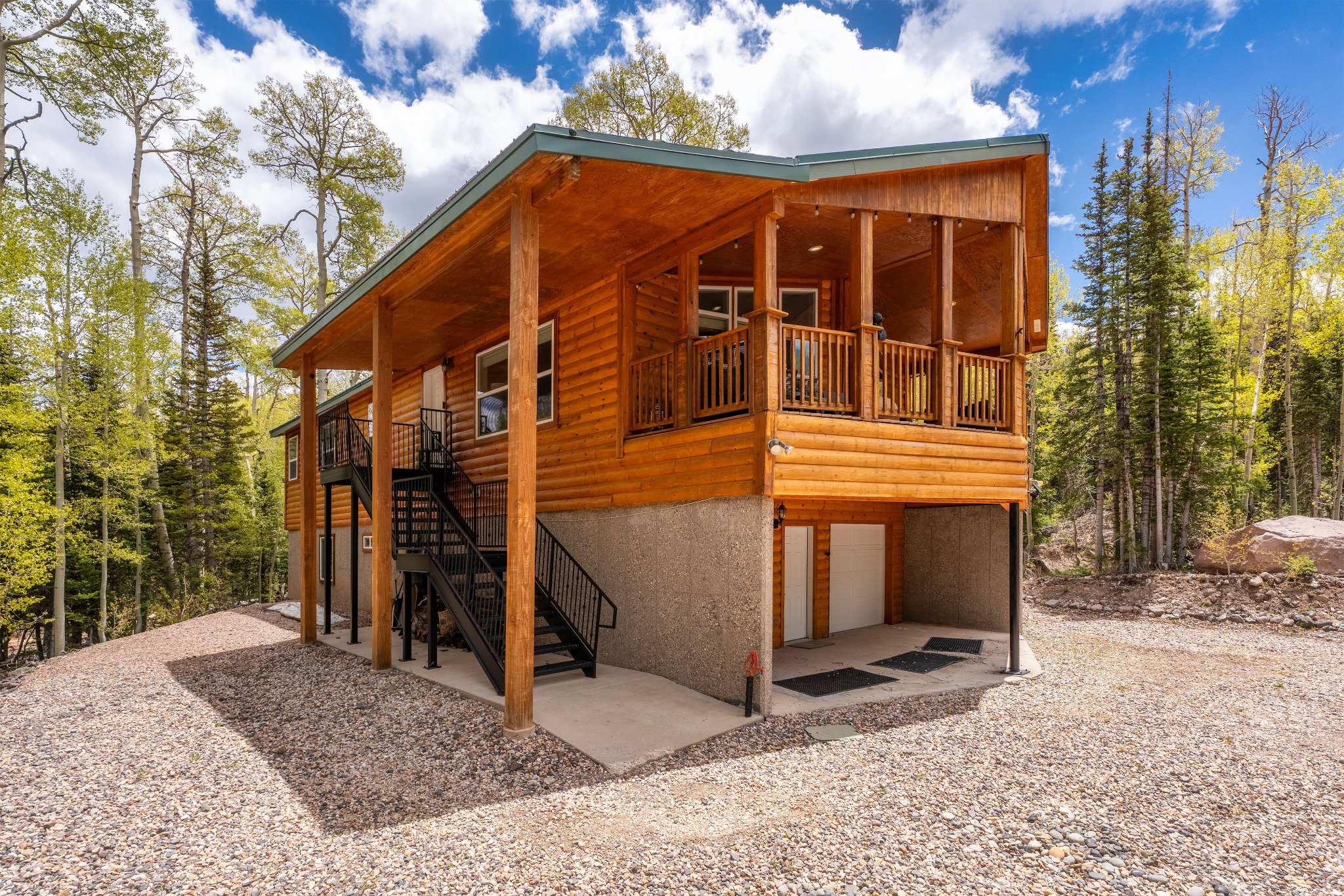 Wood-sided residence featuring an elevated covered porch, an additional exterior staircase, and a concrete foundational level with access doors