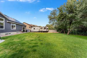 Expansive grassy yard with mature trees and a dark gray stucco exterior