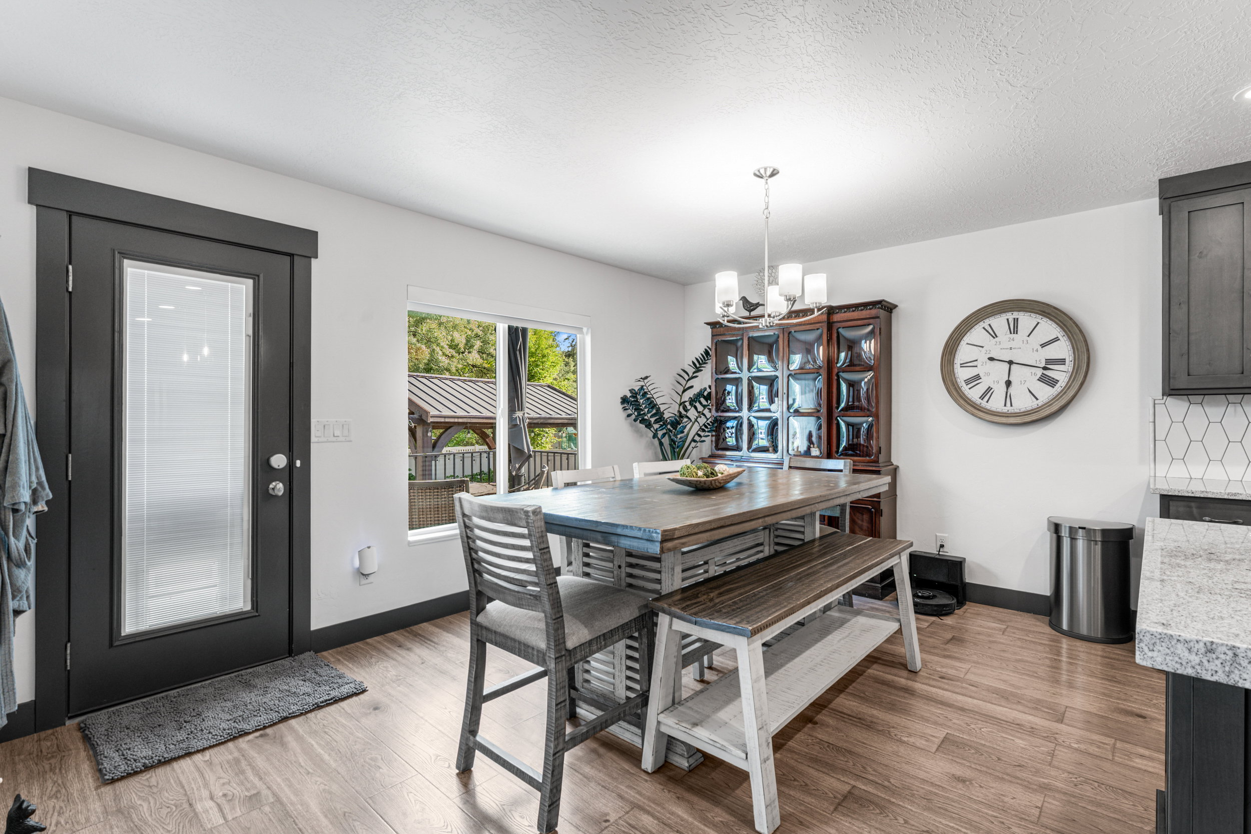 Wood-finish flooring throughout a dining area with a dark-framed glass-paneled exterior door