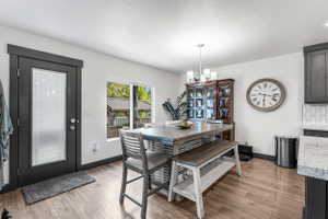 Wood-finish flooring throughout a dining area with a dark-framed glass-paneled exterior door