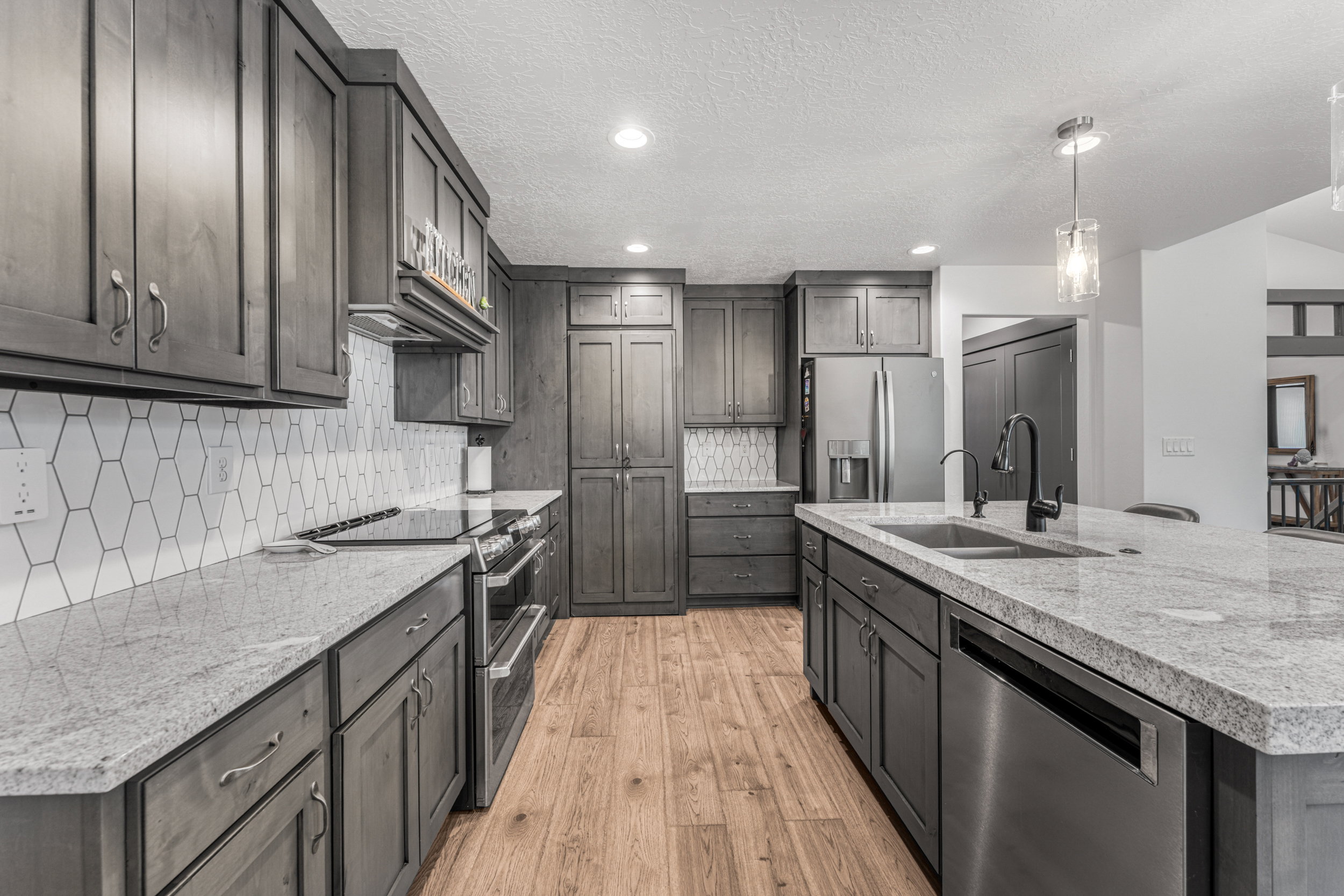 Contemporary kitchen with gray cabinetry, light-toned countertops, and stainless steel appliances