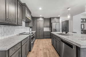 Contemporary kitchen with gray cabinetry, light-toned countertops, and stainless steel appliances