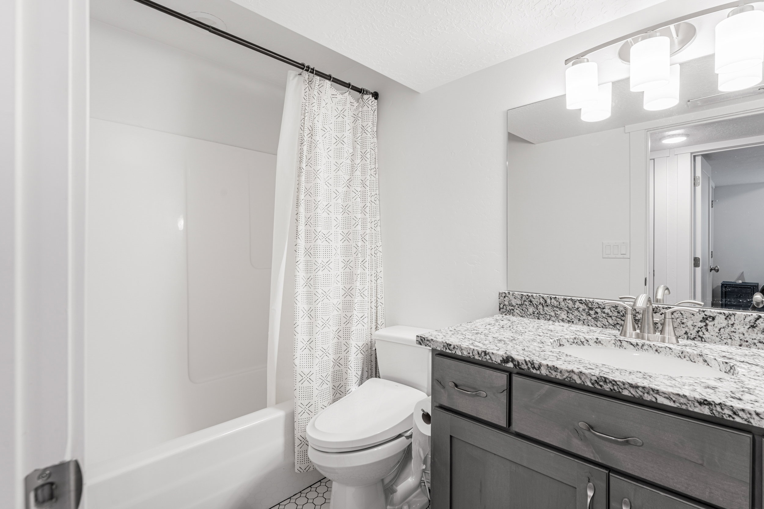 Bathroom featuring a white tub-shower combination, a vanity with a light-colored countertop, and a built-in mirror