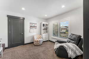 Recessed lighting illuminates the room, featuring a window with white plantation shutters and a dark gray door with coordinating trim and baseboard