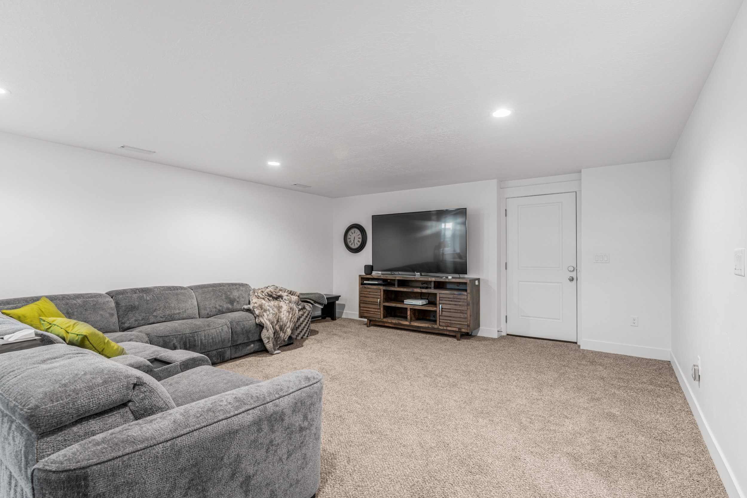 Spacious living area featuring neutral carpet flooring, recessed lighting, and white baseboards